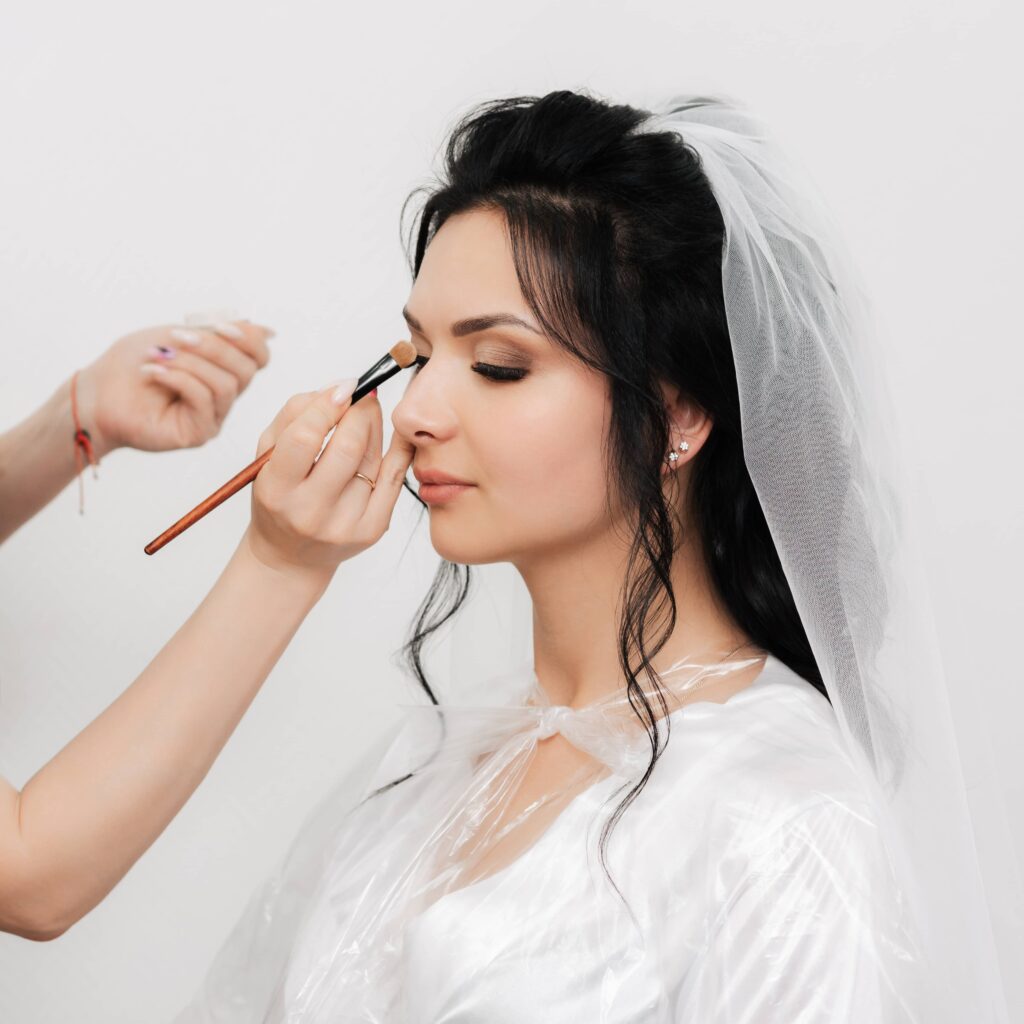 Make-up artist applica l'ombretto a una sposa